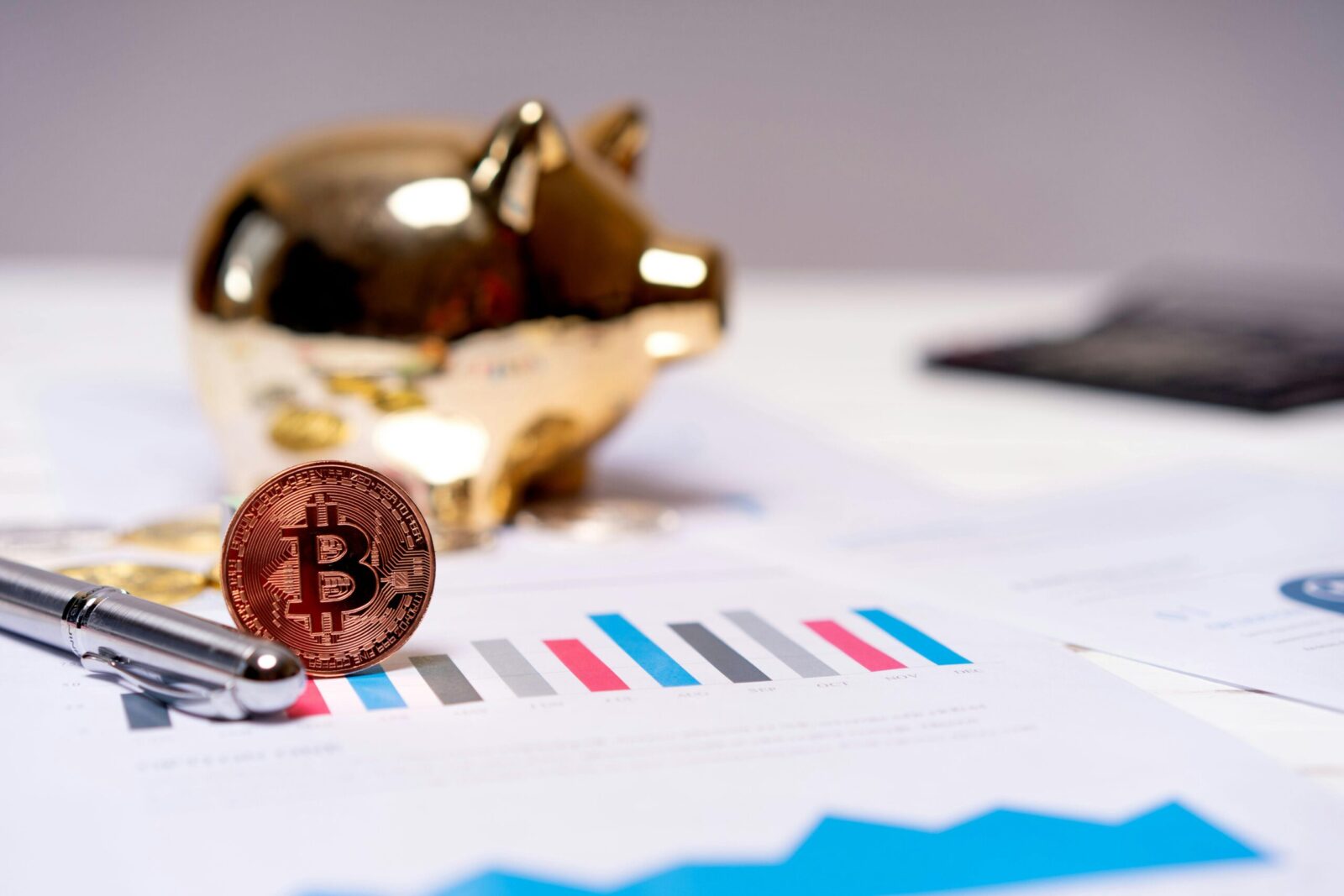 A Bitcoin coin on financial charts with a gold piggy bank, symbolizing modern finance.