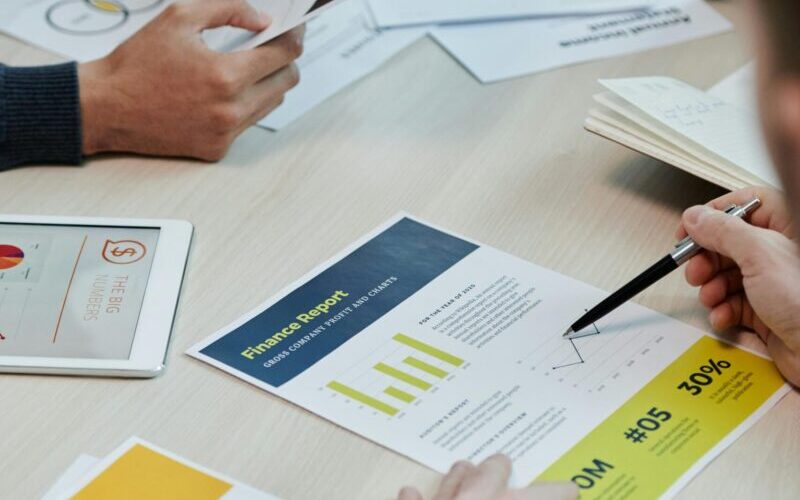 Professionals working together in an office, analyzing financial reports and documents with focus on graphs and teamwork.